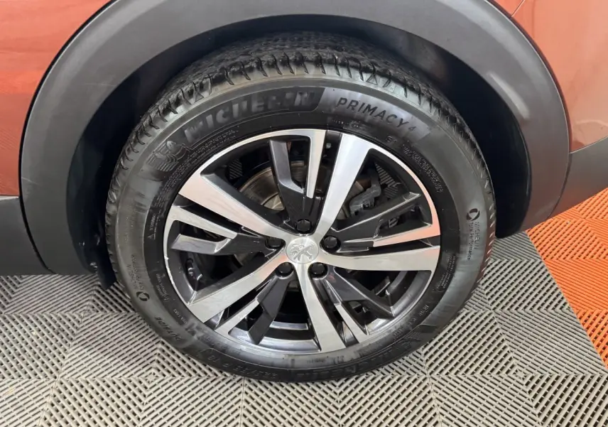 Gros plan sur la roue avant gauche orange d’un Peugeot 3008 avec jante alliage bicolore et pneu Michelin Primacy 4.