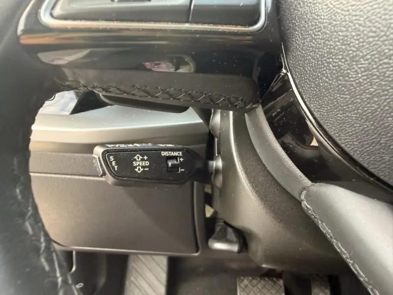 Gros plan sur la commande de régulateur de vitesse à gauche du volant d’une Audi A3 Berline gris foncé métal 2022.