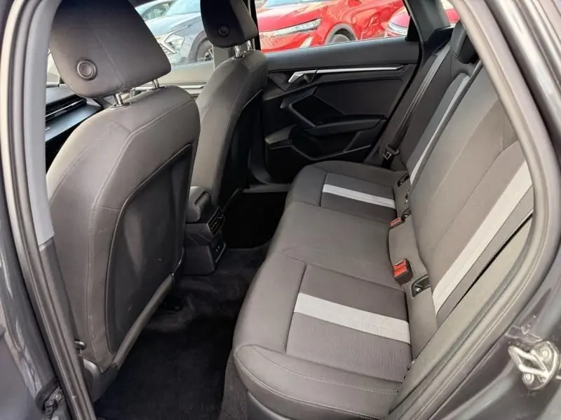 Vue intérieure sur la banquette arrière de l'Audi A3 Berline gris foncé, avec sièges tissu à bandes claires et porte côté droit ouvert.