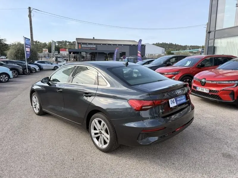 Audi A3 Berline gris foncé métal vue 3/4 arrière droit, avec jantes alliage et feux arrière LED distinctifs.