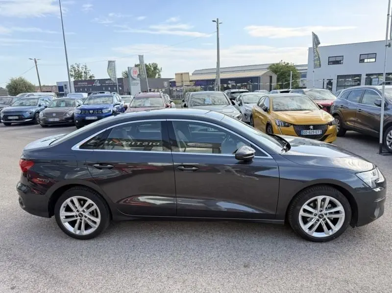 Vue de profil côté gauche d'une Audi A3 Berline 35 TFSI gris foncé métal, avec jantes alliage et lignes élégantes.