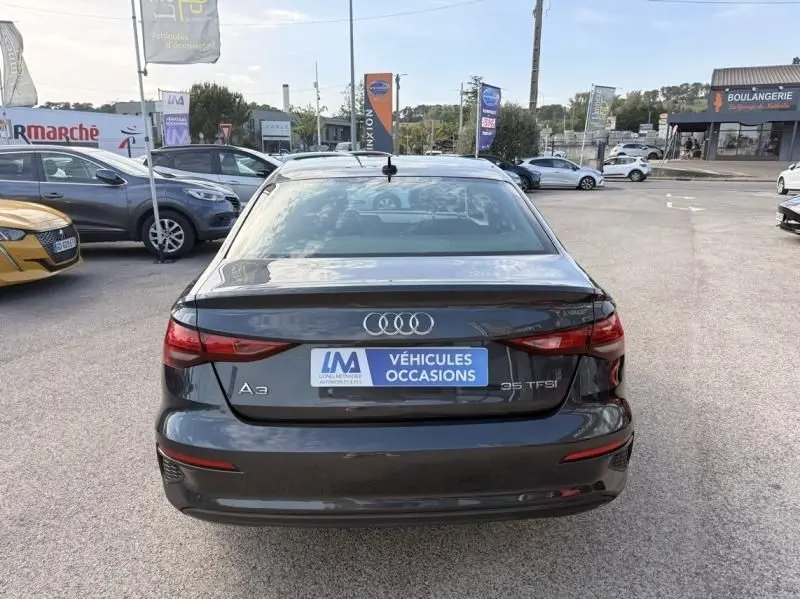 Vue arrière d'une Audi A3 Berline 35 TFSI gris foncé métal avec logo et badge visibles sur un parking extérieur.
