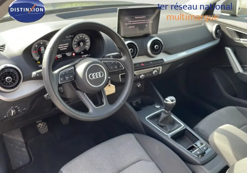 Vue intérieure de l'Audi Q2 30 TDI S-Line 2025 montrant le volant, tableau de bord numérique et levier de vitesse manuel.