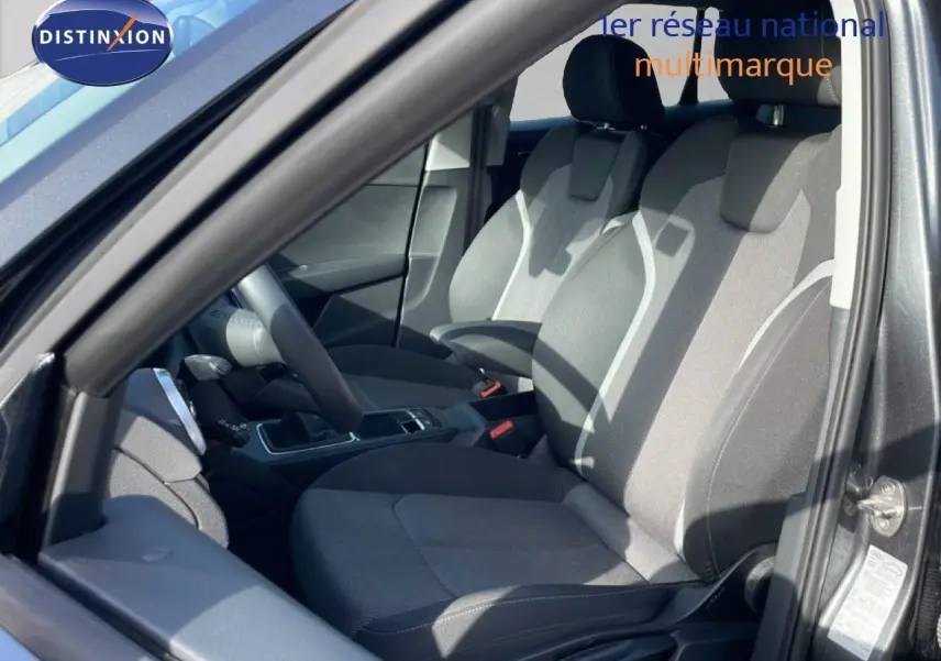 Vue intérieure côté conducteur de l'Audi Q2 30 TDI S-Line 2025 avec sièges tissu gris et volant cuir multifonction.