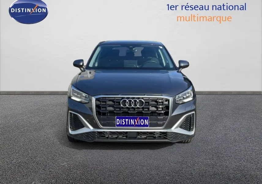 Vue frontale d'un Audi Q2 30 TDI S-Line gris Manhattan métallisé, avec calandre large et phares LED distinctifs.