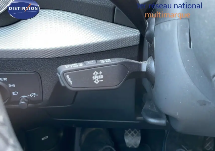 Détail intérieur montrant le levier de régulateur de vitesse et la commande d'éclairage sur un Audi Q2 gris Manhattan.
