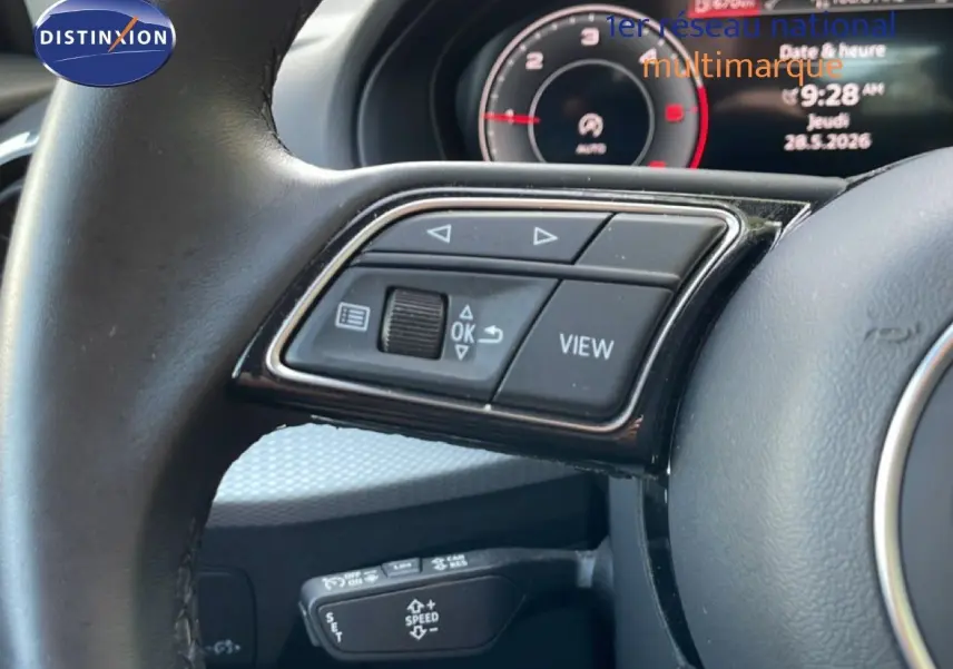 Gros plan sur le volant d’un Audi Q2 30 TDI S-Line 2025, avec commandes multifonctions et tableau de bord numérique.