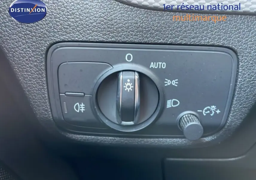 Gros plan sur le bouton de commande des phares de l'Audi Q2 30 TDI S-Line, intérieur noir texturé.