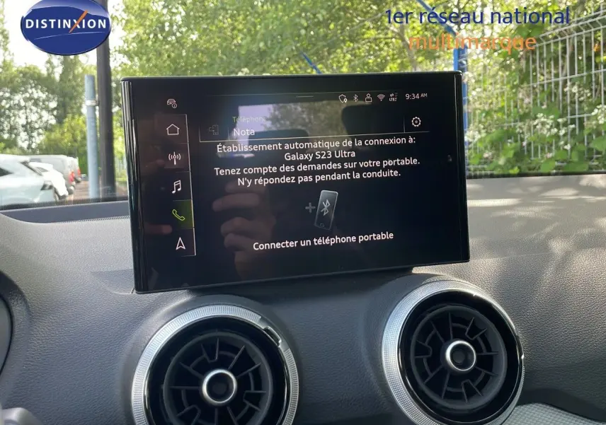 Écran tactile central affichant la connexion Bluetooth, avec deux aérateurs ronds argentés sur un tableau de bord noir.