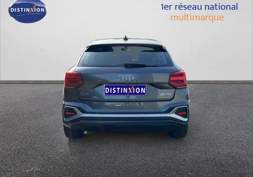Vue arrière d'un Audi Q2 gris Manhattan métal 2025 avec feux LED et logo distinctif sur fond neutre.