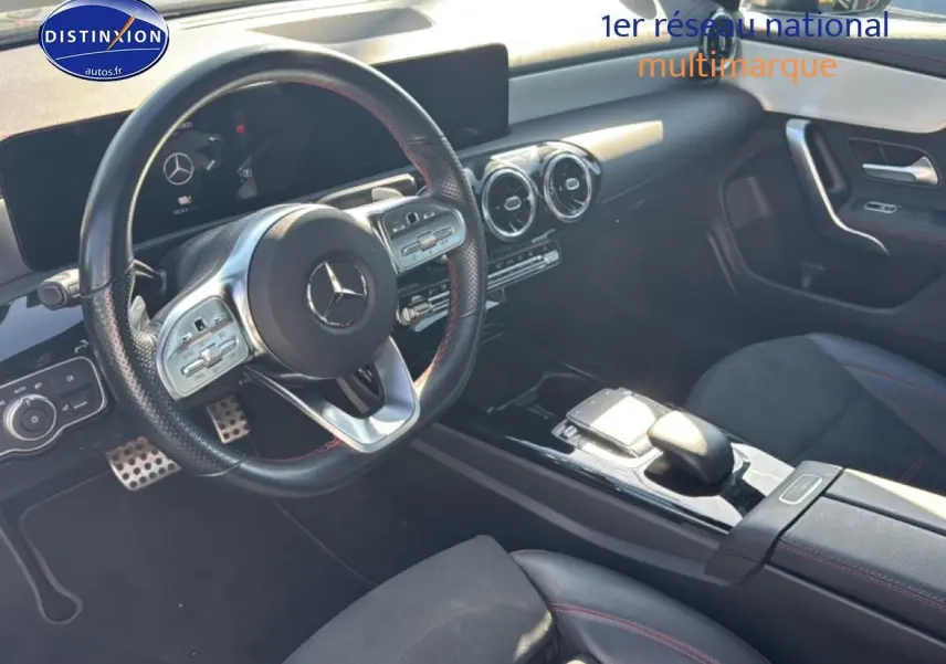 Vue intérieure côté conducteur de la Mercedes Classe CLA 250 e AMG Line 2022 avec volant cuir et finitions noires et rouges.