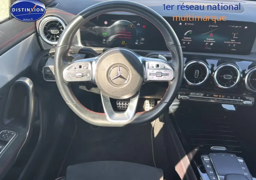 Vue intérieure centrée sur le volant cuir sport noir avec surpiqûres rouges de la Mercedes CLA 250 e AMG Line 2022.
