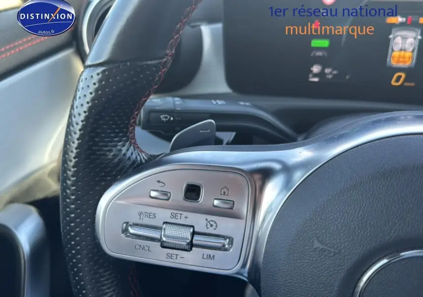 Gros plan sur le volant cuir noir avec surpiqûres rouges et commandes multifonctions d'une Mercedes Classe CLA 250 e AMG 2022.