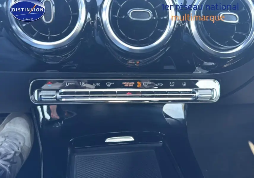 Vue rapprochée de la console centrale noire de la Mercedes Classe CLA 250 e AMG Line avec aérateurs ronds et commandes climatisation.