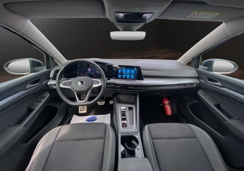 Vue intérieure avant de la Volkswagen Golf noire 2022, tableau de bord moderne avec écran tactile et volant cuir multifonctions.