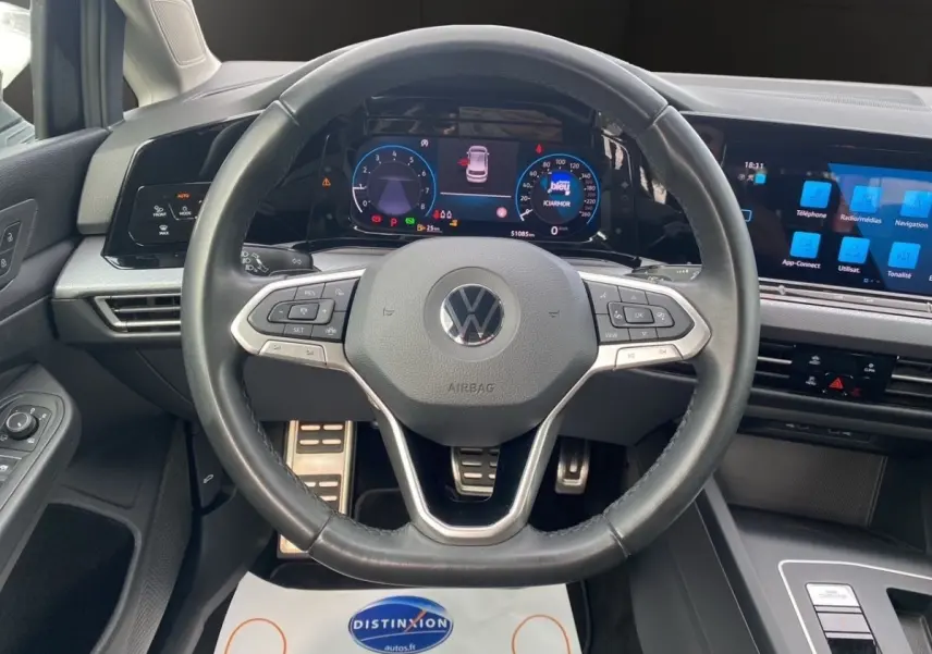 Vue intérieure centrée sur le volant cuir multifonctions et le tableau de bord numérique de la Volkswagen Golf 2022.