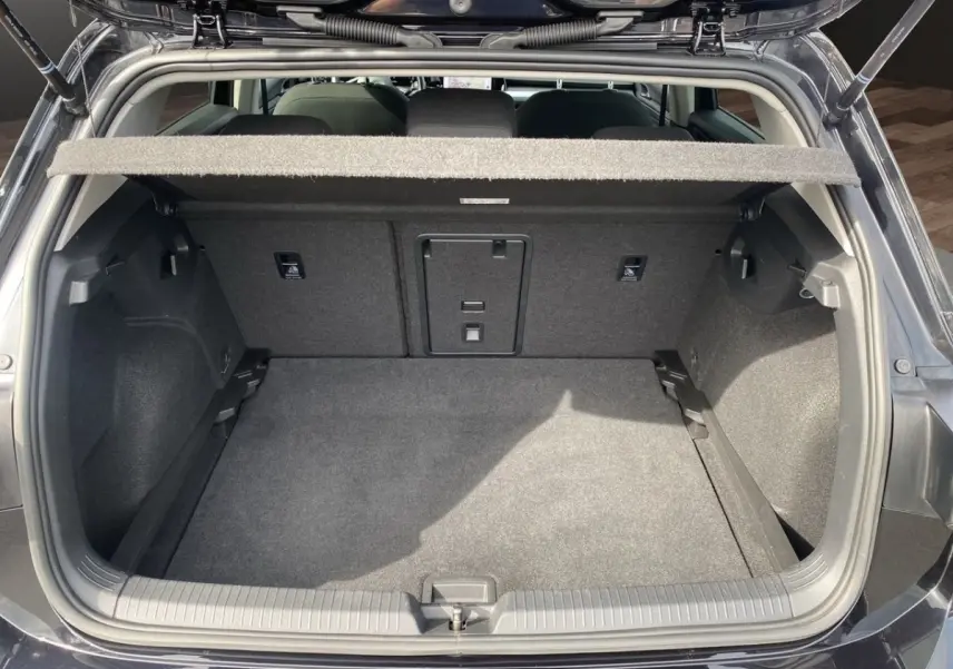 Coffre ouvert vu de l'arrière d'une Volkswagen Golf noire, montrant l'espace de chargement et la tablette cache-bagages.