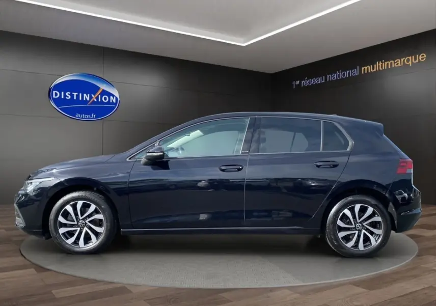 Profil côté gauche d'une Volkswagen Golf noire 2022 avec vitres surteintées dans un showroom.
