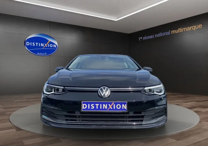 Vue frontale d'une Volkswagen Golf noire 2022 avec phares LED et plaque Distinxion en showroom.