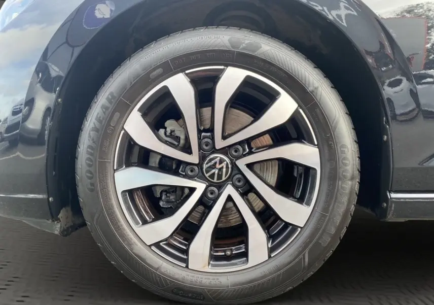 Gros plan sur la roue avant droite noire d'une Volkswagen Golf 1.0 eTSI avec jante alliage bicolore et pneu Goodyear.