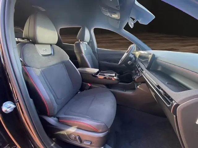 Intérieur avant du Hyundai Tucson 1.6 Hybrid noir, sièges N Line en alcantara avec surpiqûres rouges et tableau de bord moderne.