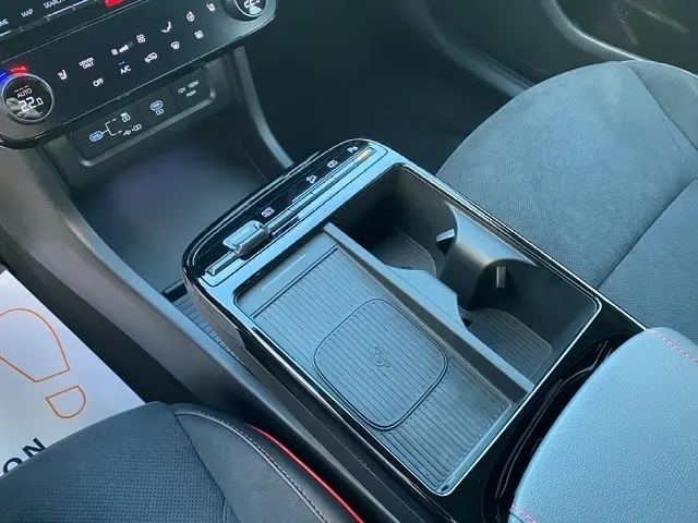 Vue rapprochée de la console centrale noire du Hyundai Tucson 1.6 Hybrid 2026 avec chargeur induction et porte-gobelets.