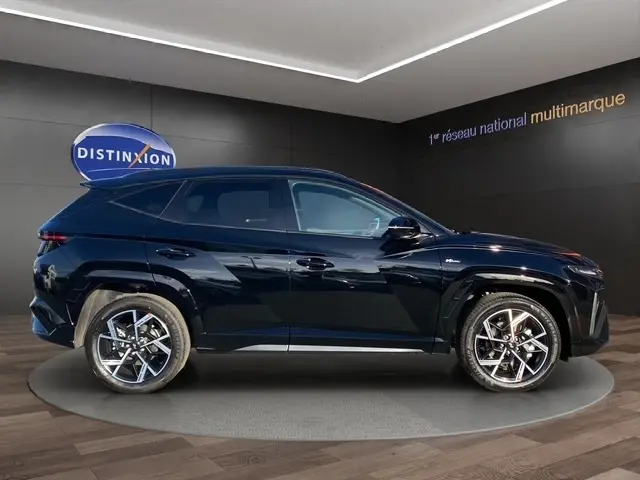 Vue latérale droite du Hyundai Tucson 1.6 Hybrid N Line noir, avec jantes alliage et hayon motorisé visible en arrière-plan.