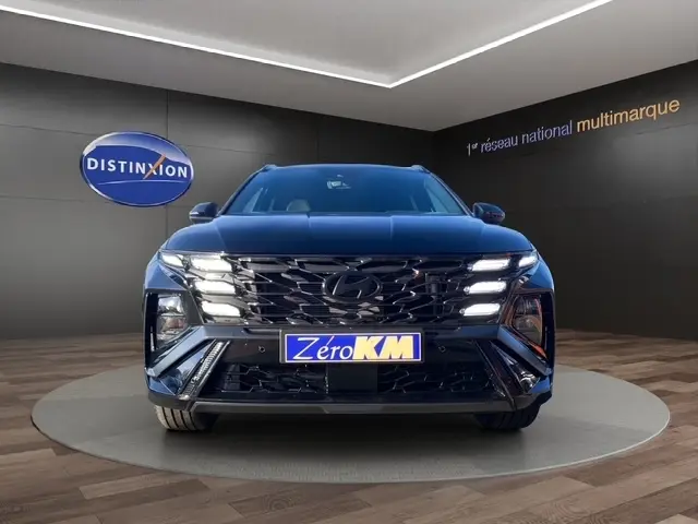 Vue avant d'un Hyundai Tucson noir 2026 avec calandre imposante et phares LED allumés en showroom.