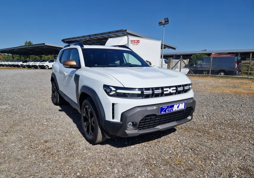 Vue 3/4 avant gauche d'un Dacia Duster blanc 2026 avec rétroviseurs bronze et calandre distinctive noire.