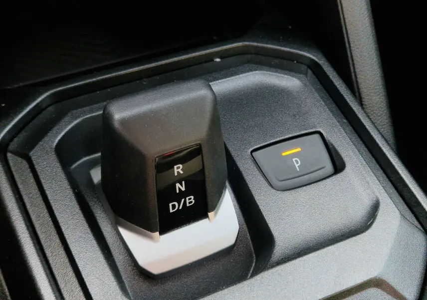 Gros plan sur le levier de vitesses automatique noir et gris avec bouton de parking éclairé dans un Dacia Duster blanc 2026.