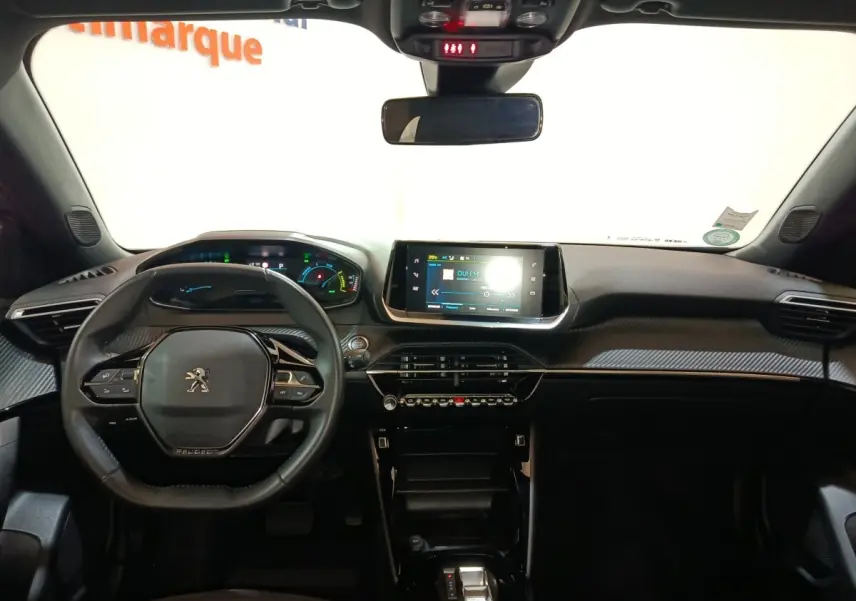 Vue intérieure frontale du tableau de bord et volant cuir noir du Peugeot E-2008 électrique gris clair 2023 avec écran tactile central.