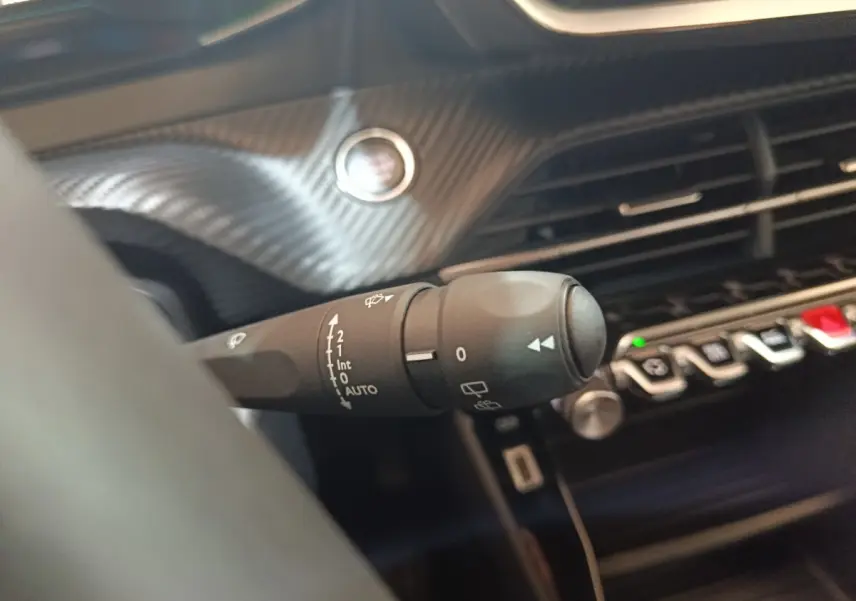Gros plan sur la commande des essuie-glaces côté gauche du tableau de bord du Peugeot E-2008 électrique gris clair.