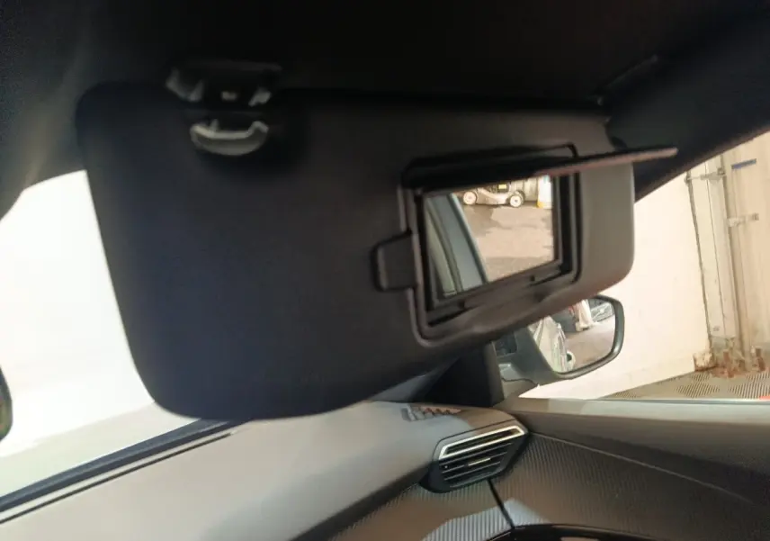 Détail intérieur montrant le pare-soleil avec miroir ouvert côté conducteur du Peugeot E-2008 électrique gris clair 2023.