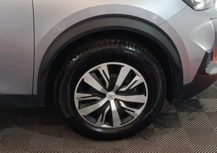 Gros plan sur la roue avant droite d’un Peugeot E-2008 électrique gris clair avec jante au design moderne.