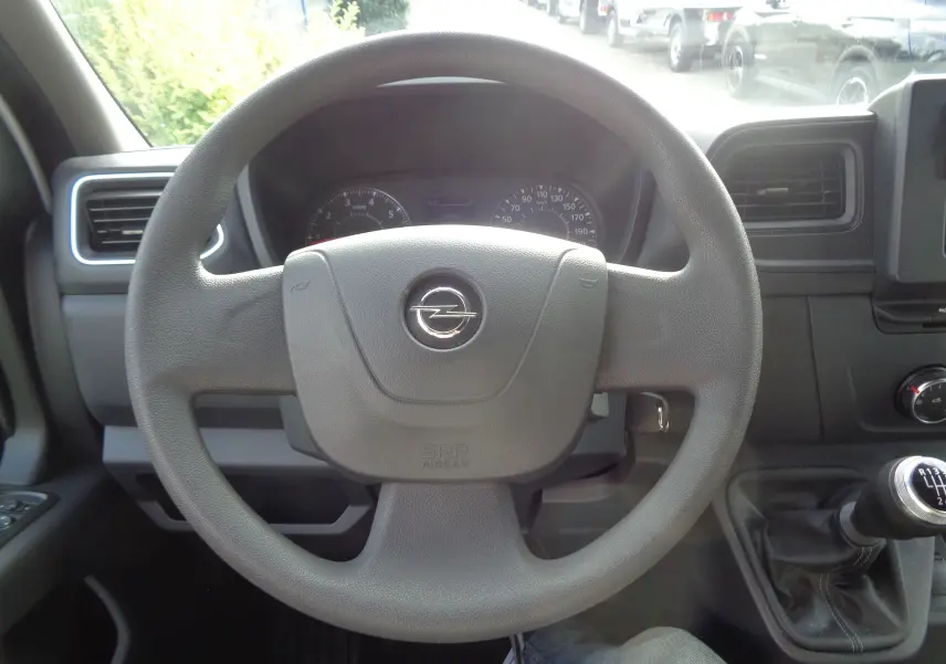Vue intérieure centrée sur le volant Opel du Movano Fourgon blanc polaire, avec levier de vitesses manuel visible à droite.