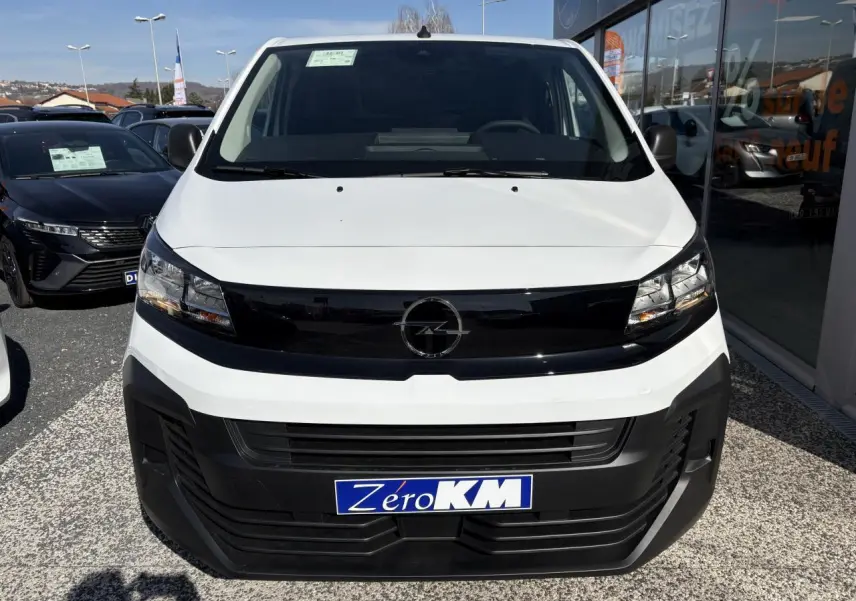 Vue frontale d'un Opel Vivaro blanc avec calandre noire brillante et plaque Zéro KM visible.