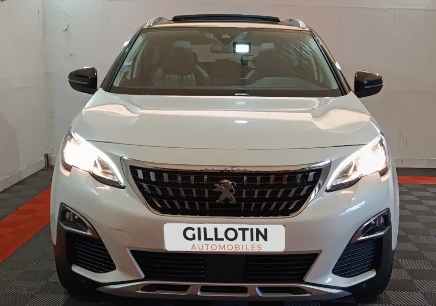 Vue frontale d'un Peugeot 3008 blanc avec phares allumés et calandre noire distinctive.