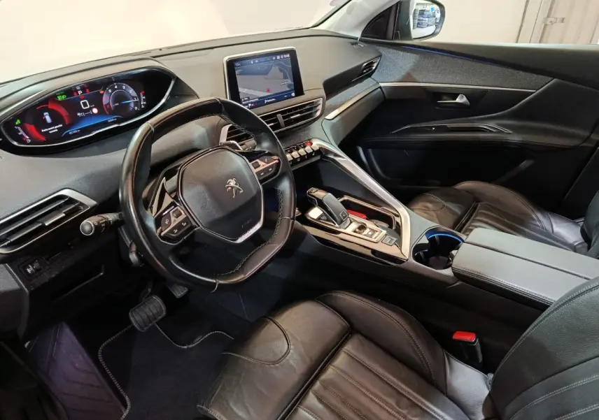 Vue intérieure côté conducteur du Peugeot 3008 avec volant cuir, écran tactile central et sièges en cuir noirs.