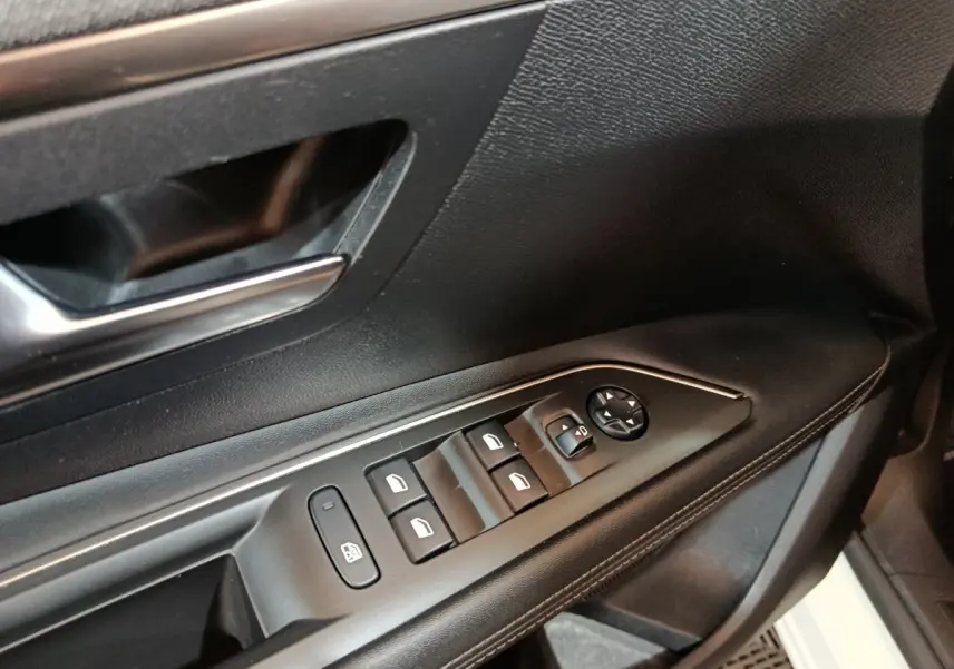 Gros plan sur la commande des vitres côté gauche d’une Peugeot 3008 blanc, avec poignée de porte noire.