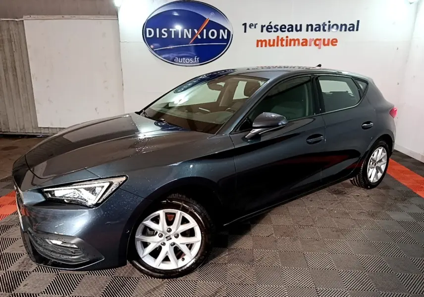 Vue 3/4 avant droit d'une SEAT Leon gris clair 2023 avec jantes alliage et phares LED ellipsoïdaux.