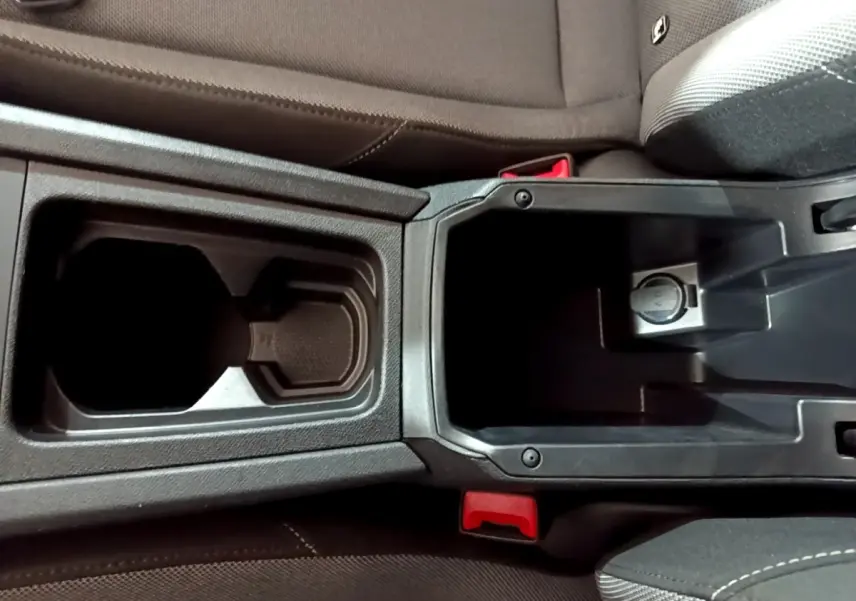 Vue plongeante sur la console centrale noire avec porte-gobelets et rangement du SEAT Leon gris clair 2023.