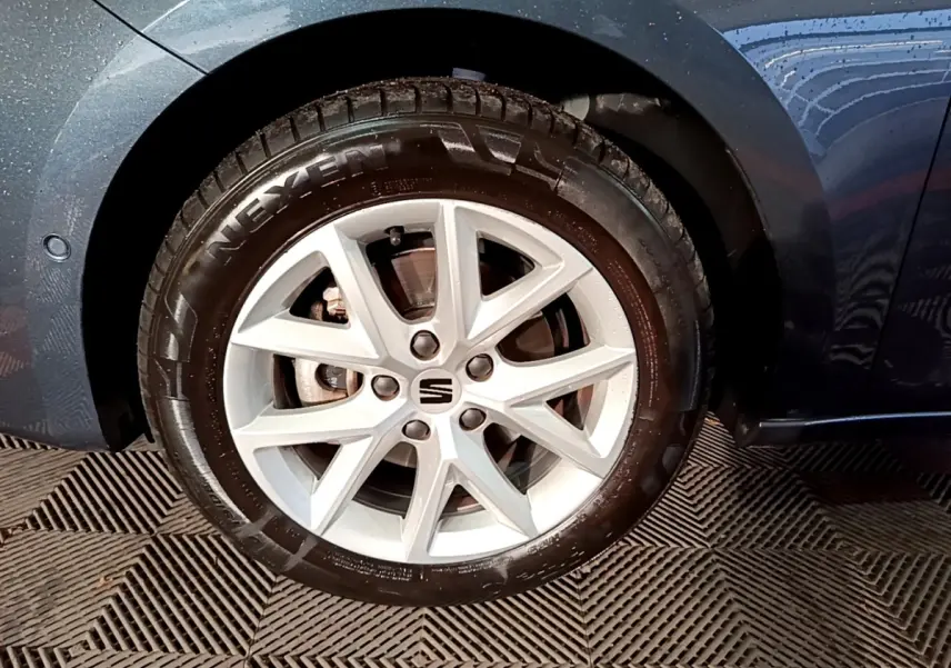 Gros plan sur la roue avant droite gris clair d'une SEAT LEON 2023 avec jante alliage et logo central SEAT.
