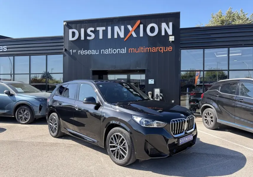 BMW X1 noir saphir vue 3/4 avant droit, avec calandre chromée et jantes alliage 18 pouces bicolores.