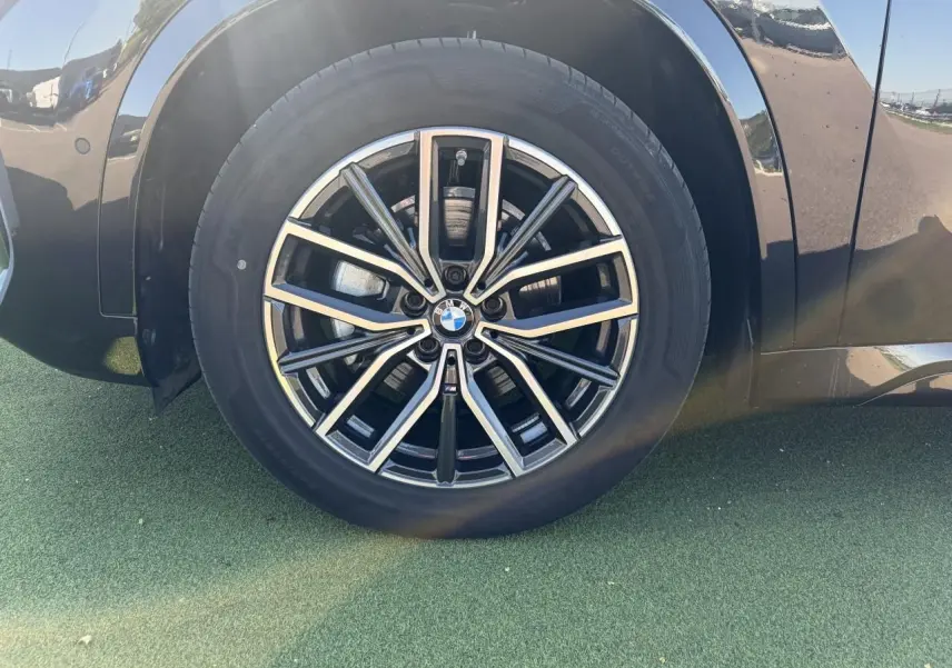 Gros plan sur la roue avant gauche du BMW X1 noir saphir, mettant en valeur la jante alliage 18 pouces bicolore style 838 M.