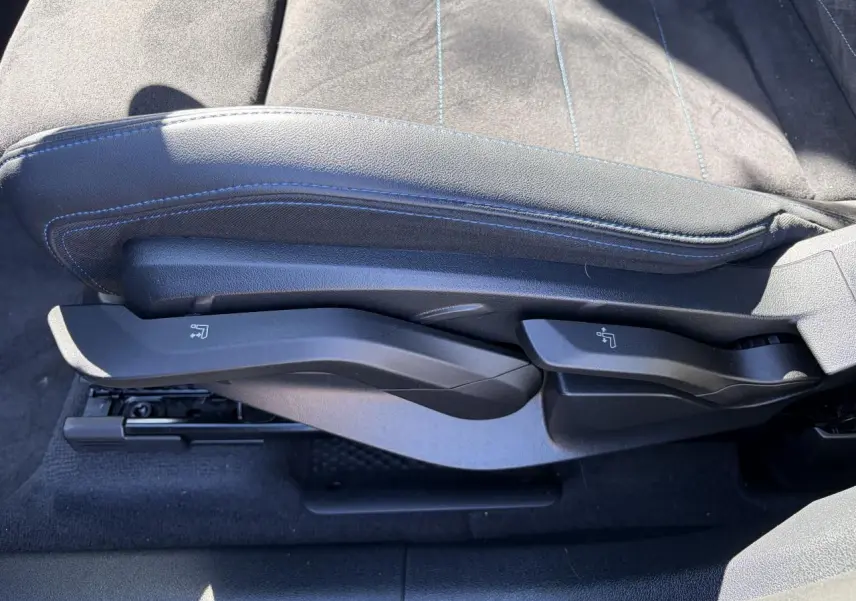 Gros plan sur les commandes latérales du siège avant en Alcantara noir avec surpiqûres bleues du BMW X1 2025.