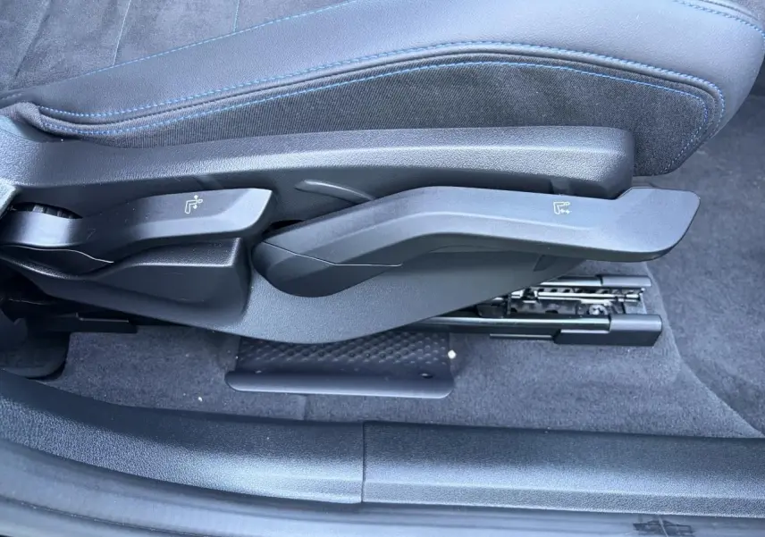 Gros plan sur les commandes latérales du siège avant en Alcantara noir avec surpiqûres bleues du BMW X1 noir Saphir 2025.