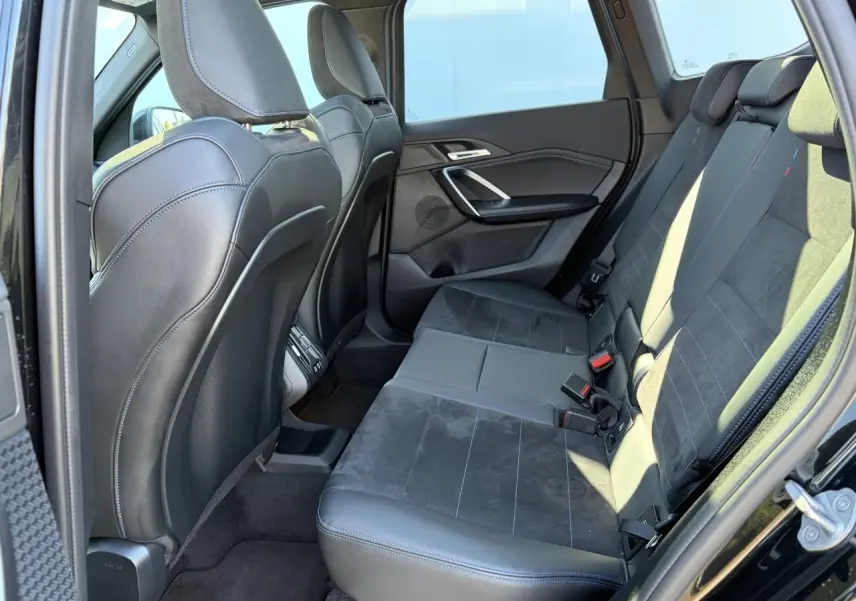Vue intérieure côté gauche de la banquette arrière en cuir noir avec surpiqûres bleues du BMW X1 2025 noir saphir.