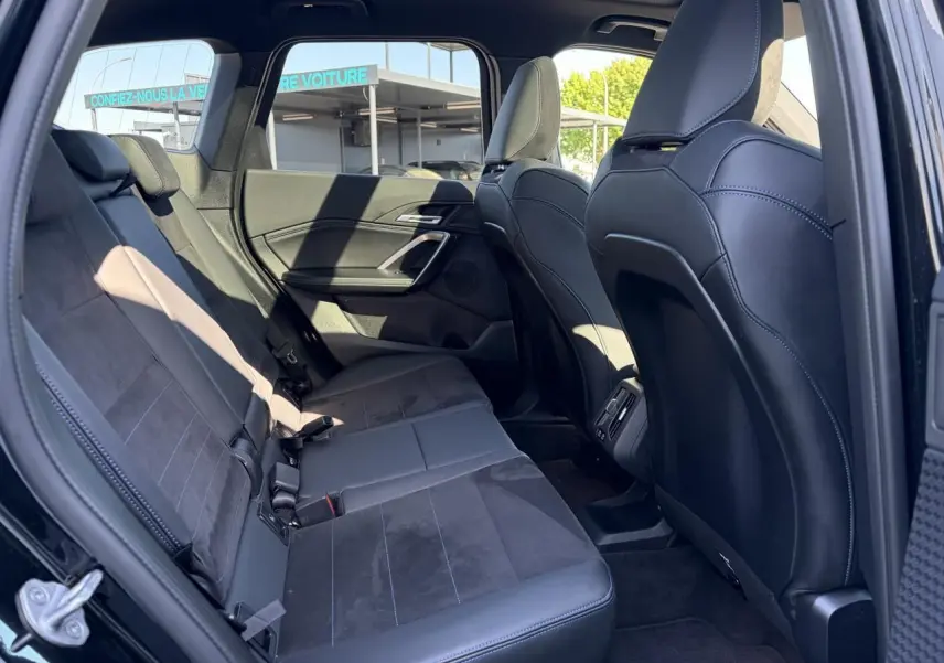 Vue intérieure côté gauche de la banquette arrière en Alcantara noir avec surpiqûres bleues du BMW X1 noir Saphir 2025.