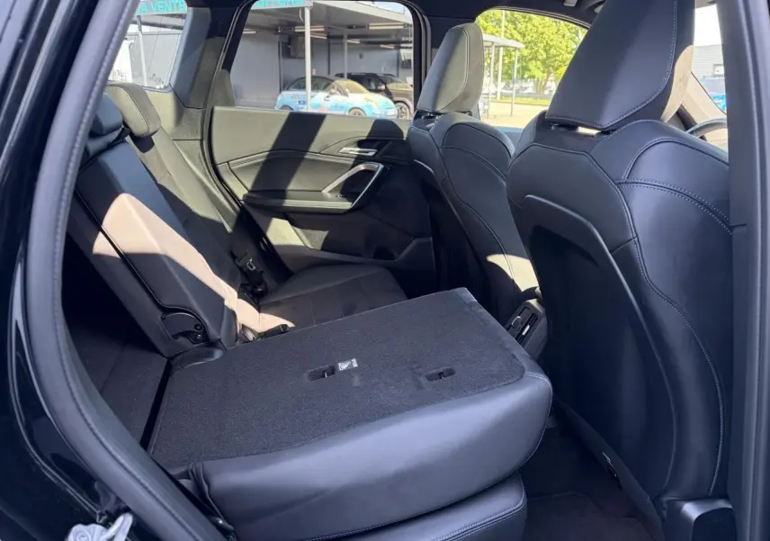Vue intérieure côté gauche de la banquette arrière noire rabattue partiellement dans un BMW X1 noir Saphir 2025.