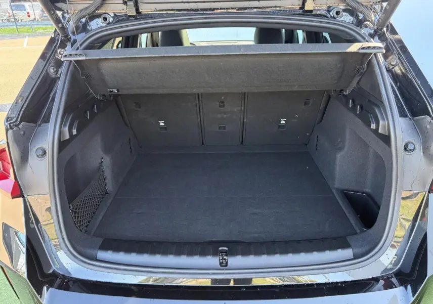 Coffre ouvert vu de l'arrière d'un BMW X1 noir saphir avec filet de séparation et banquette arrière rabattable.